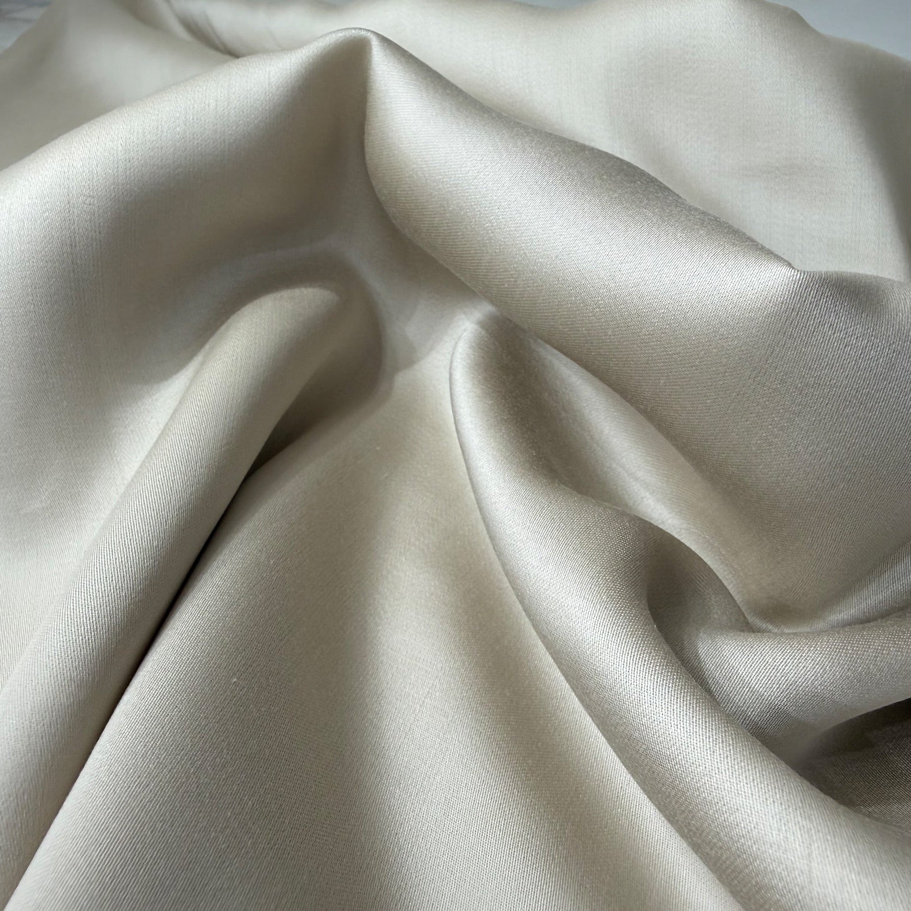 Nordhavn Living Aurora Satin Bettwäsche in Sandbeige (Drift Light): Nahaufnahme der sanften Wellen im Stoff, die den seidigen Griff und den natürlichen Glanz des Tencels zeigen.