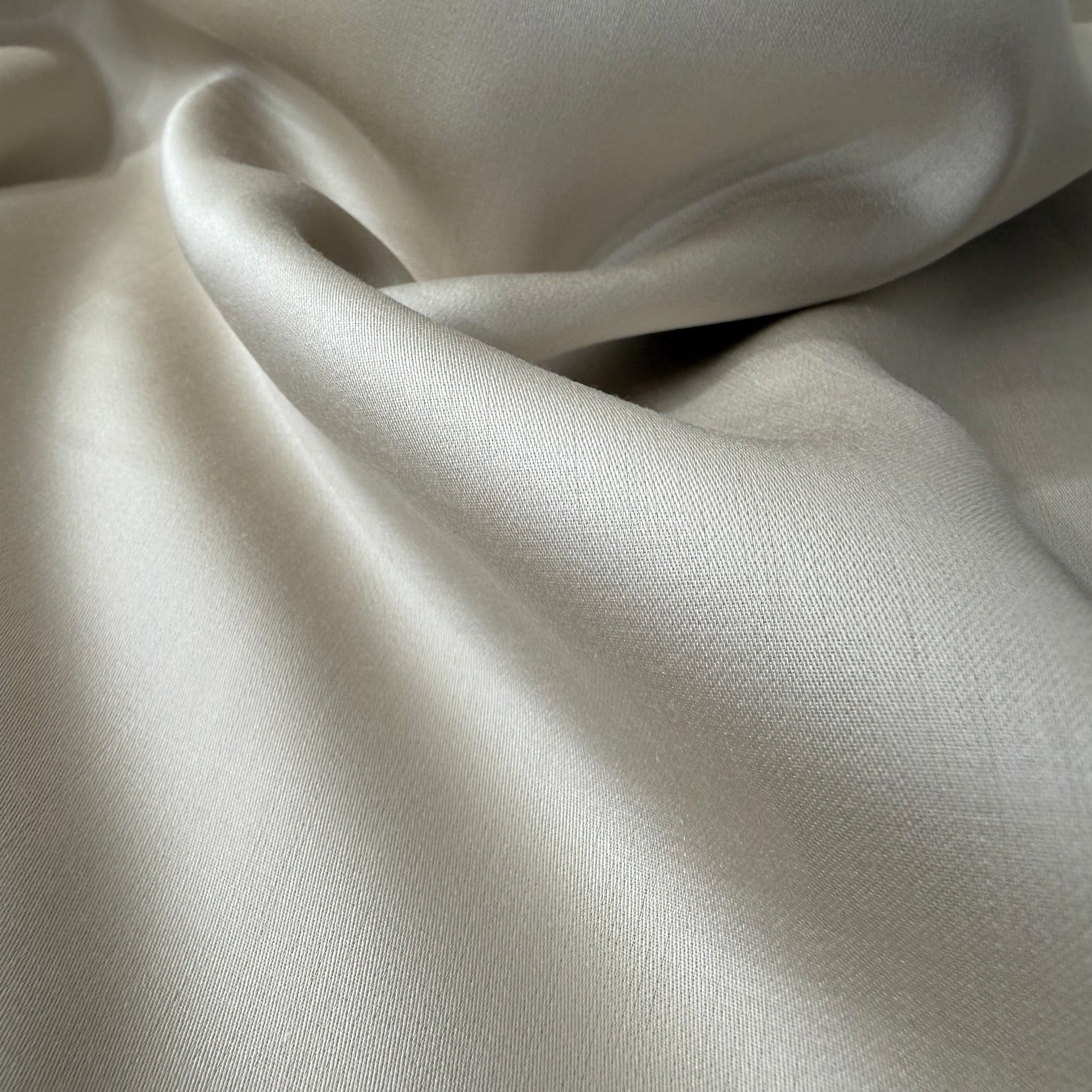 Nordhavn Living Aurora Satin Bettwäsche in Sandbeige (Drift Light): Detailaufnahme der eleganten Drapierung, die den edlen Schimmer und die Wärme des Farbtons hervorhebt.