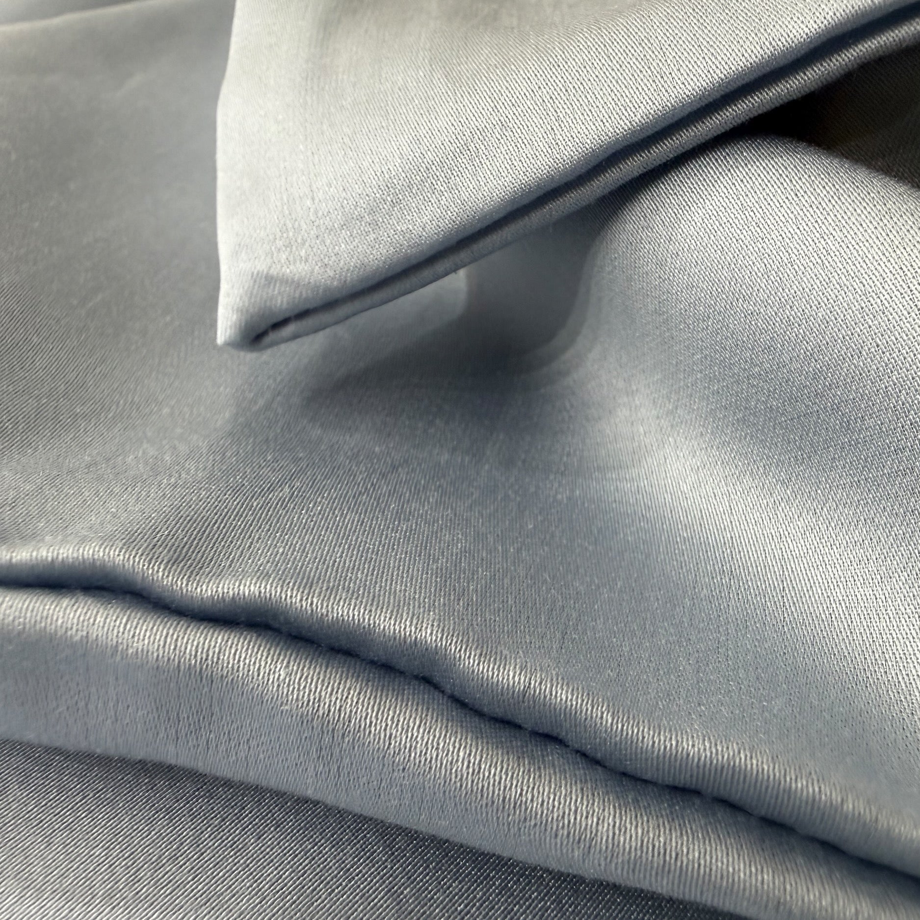 Nordhavn Living Aurora Satin Bettwäsche in Eisgrau (Frost Haze): Detailaufnahme der übereinanderliegenden Stoffbahnen, die die dichte Webung und den kühlen, eleganten Glanz der Tencel-Faser hervorheben.