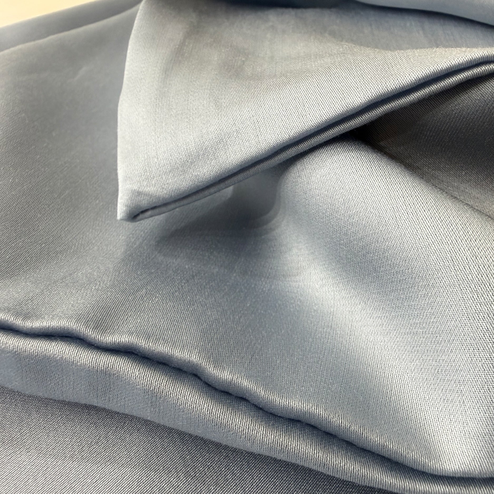 Nordhavn Living Aurora Satin Bettwäsche in Kühlem Graublau (Frost Haze): Detailansicht der weich gefalteten Stofflagen mit silbrig-blauem Schimmer und edler Tencel-Textur.