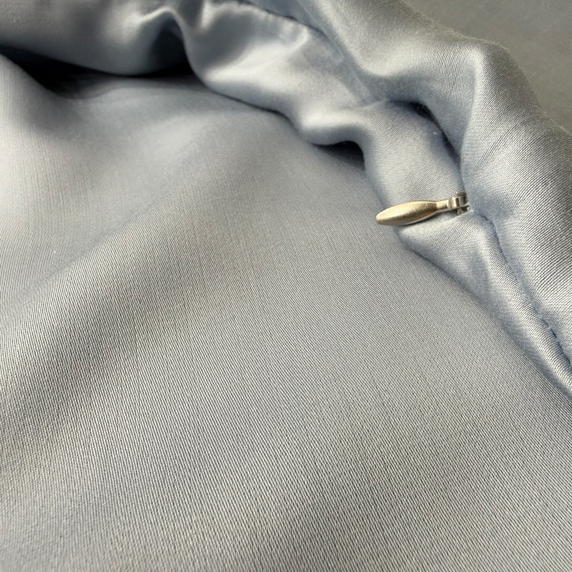 Nordhavn Living Aurora Satin Bettwäsche in Kühlem Graublau (Frost Haze): Detailbild des unter einer Stoffleiste verborgenen Reißverschlusses für eine glatte, ungestörte Oberfläche.