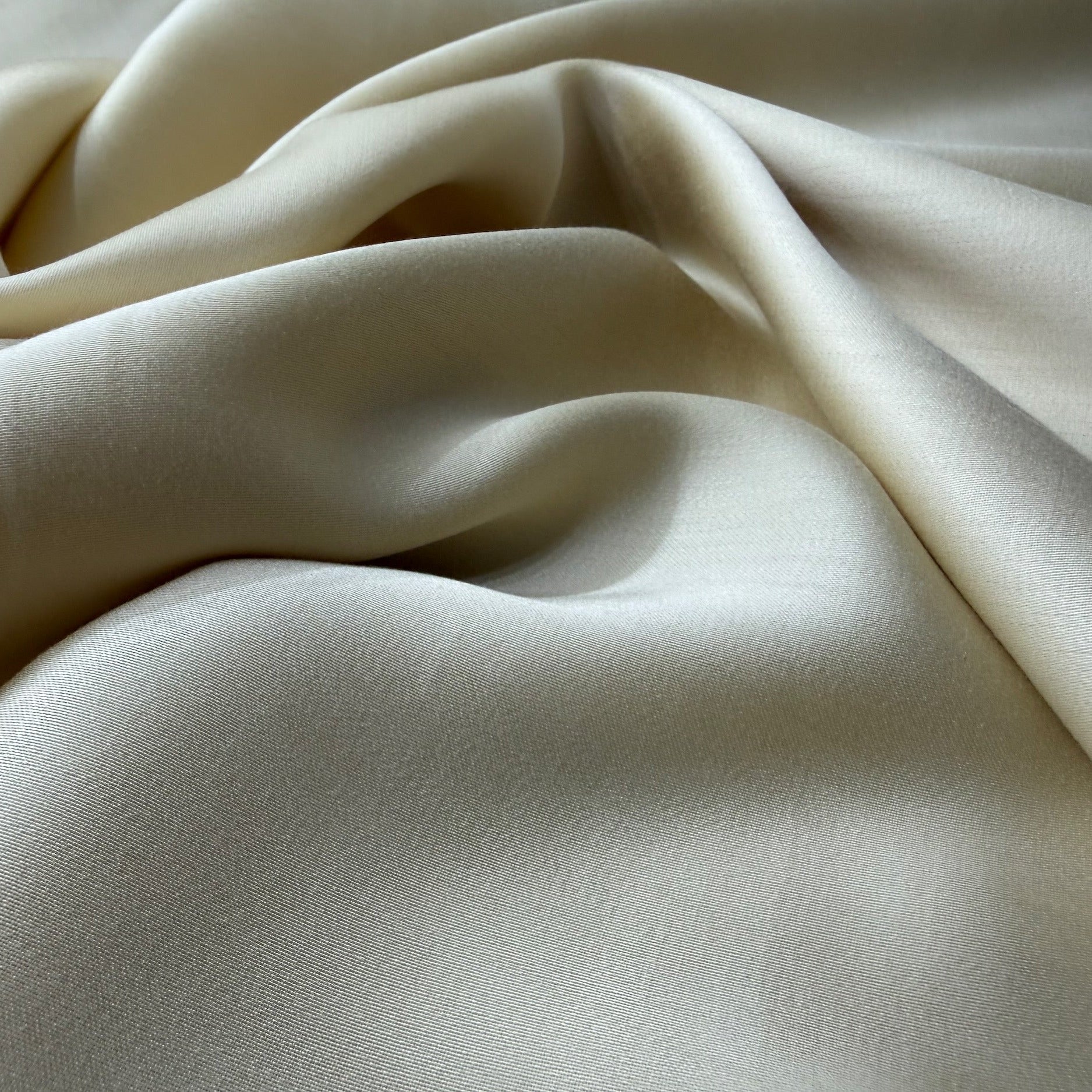 Nordhavn Living Aurora Satin Bettwäsche in Hellem Greige (Harvest Dust): Nahaufnahme der sanft geschwungenen Stoffwellen, die den lebendigen Glanz und die seidige Geschmeidigkeit des Tencel-Satins betonen.