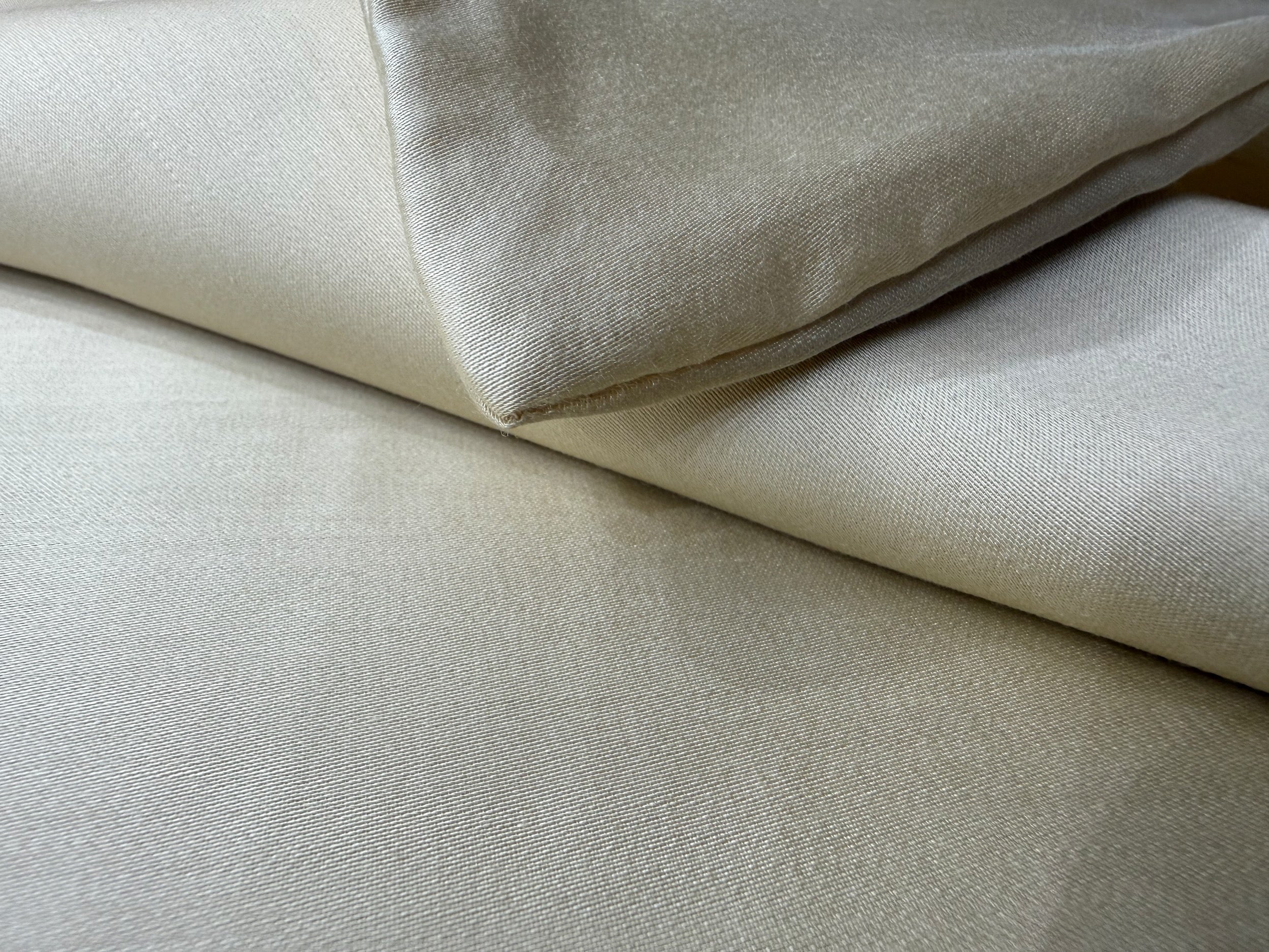 Nordhavn Living Aurora Satin Bettwäsche in Hellem Greige (Harvest Dust): Detailansicht der weich gefalteten Stofflagen, die den pudrigen, natürlichen Schimmer des Tencel-Satins zeigen.