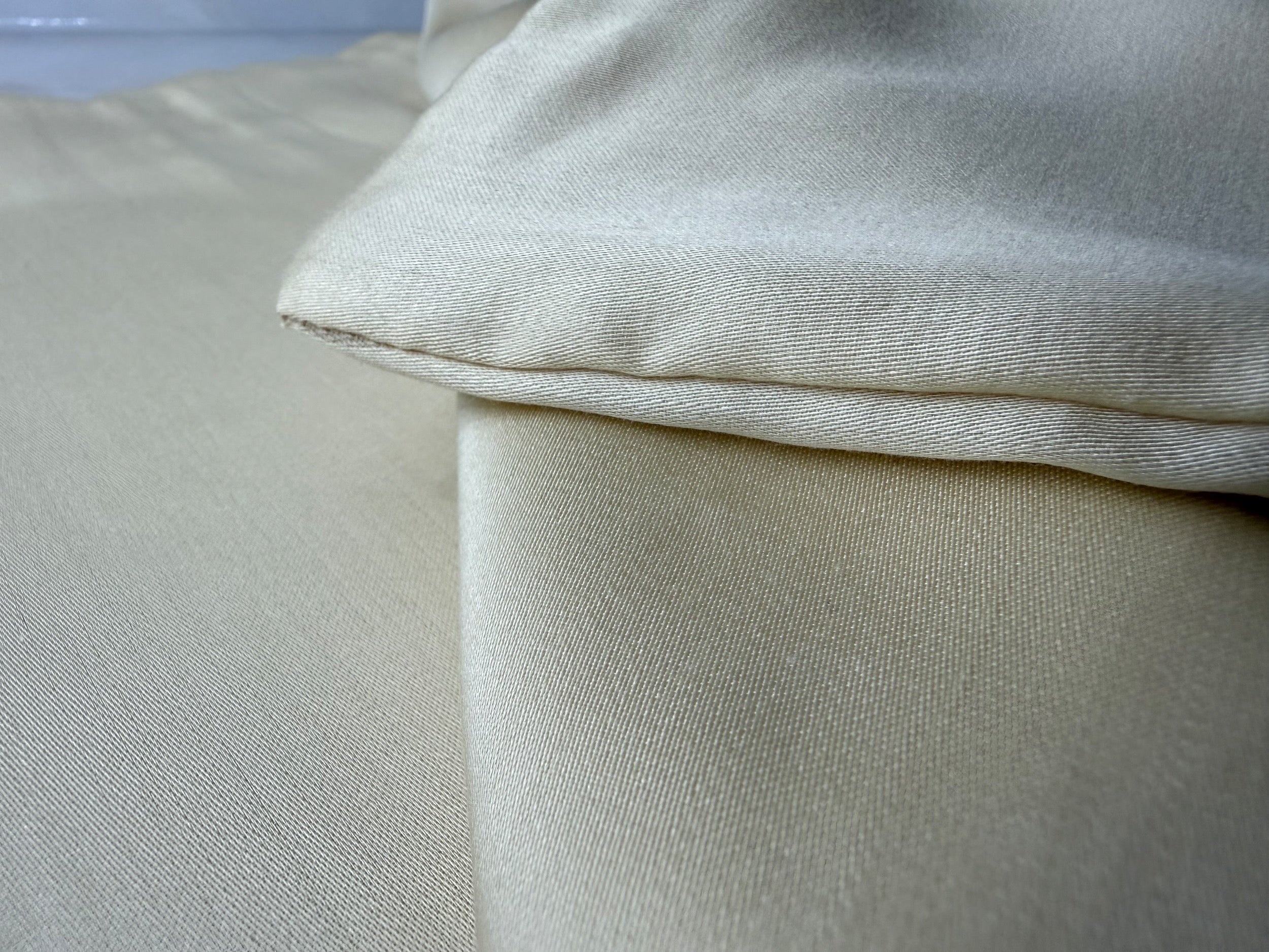 Nordhavn Living Aurora Satin Bettwäsche in Hellem Greige (Harvest Dust): Makro-Aufnahme der feinen Satin-Webstruktur und der weichen Stofflagen mit ihrem natürlichen, warmen Schimmer.