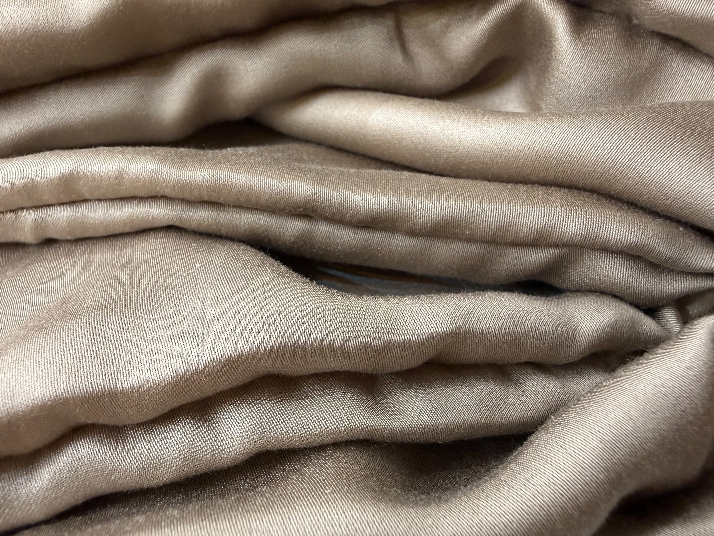 Nordhavn Living Aurora Satin Bettwäsche in Warmem Lehmgrau (Still Clay): Nahaufnahme der voluminös drapierten Stofflagen, die den sanften, erdigen Glanz und die weiche Textur des Satins einfangen.