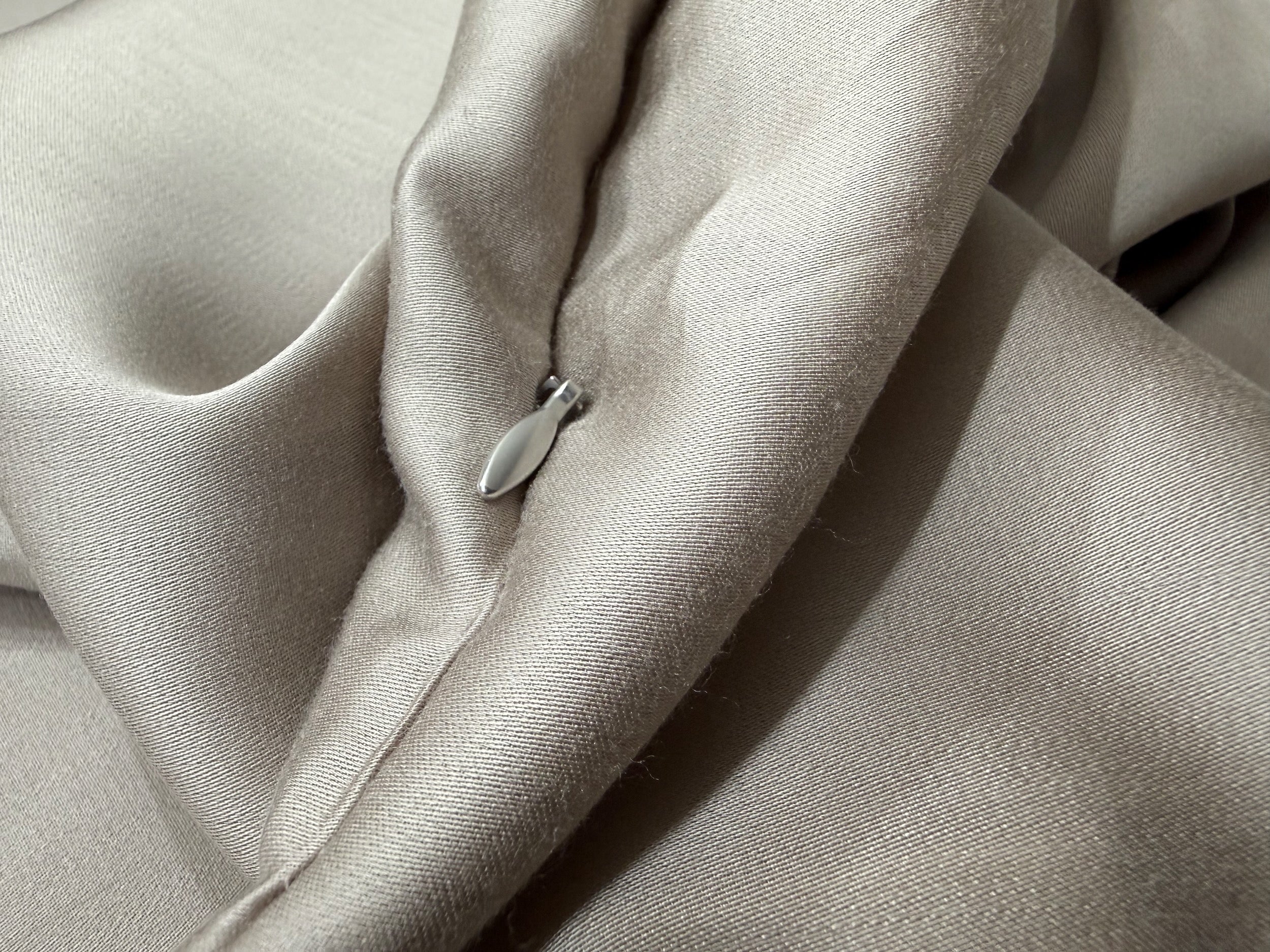 Nordhavn Living Aurora Satin Bettwäsche in Warmem Lehmgrau (Still Clay): Detailaufnahme des hochwertigen Reißverschlusses mit elegantem Metall-Zipper, der sanft in die weichen Stofffalten eingebettet ist.