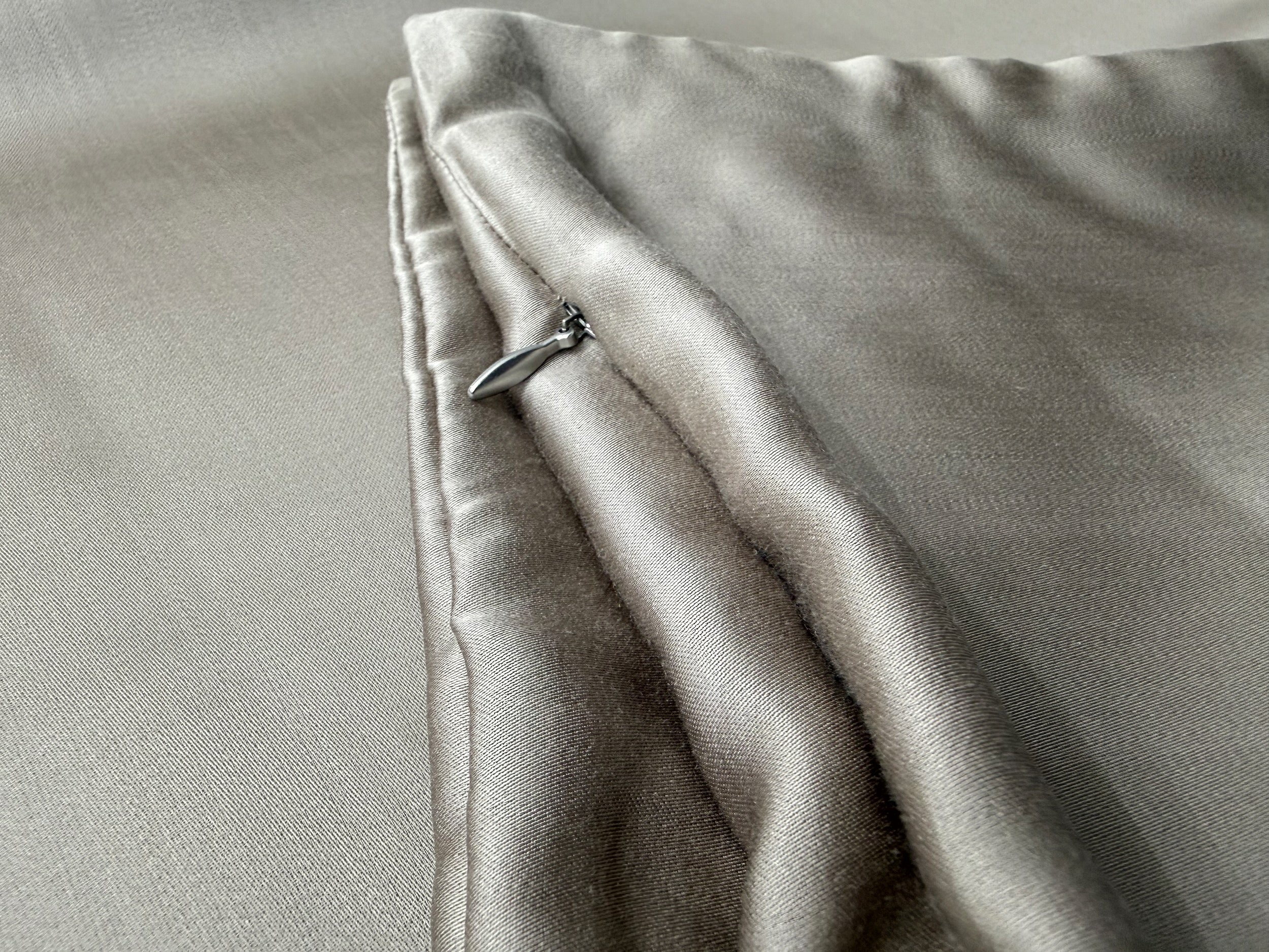 Nordhavn Living Aurora Satin Bettwäsche in Warmem Lehmgrau (Still Clay): Detailansicht der präzisen Kantenverarbeitung und des verdeckt eingenähten Reißverschlusses mit edlem Metall-Schieber.