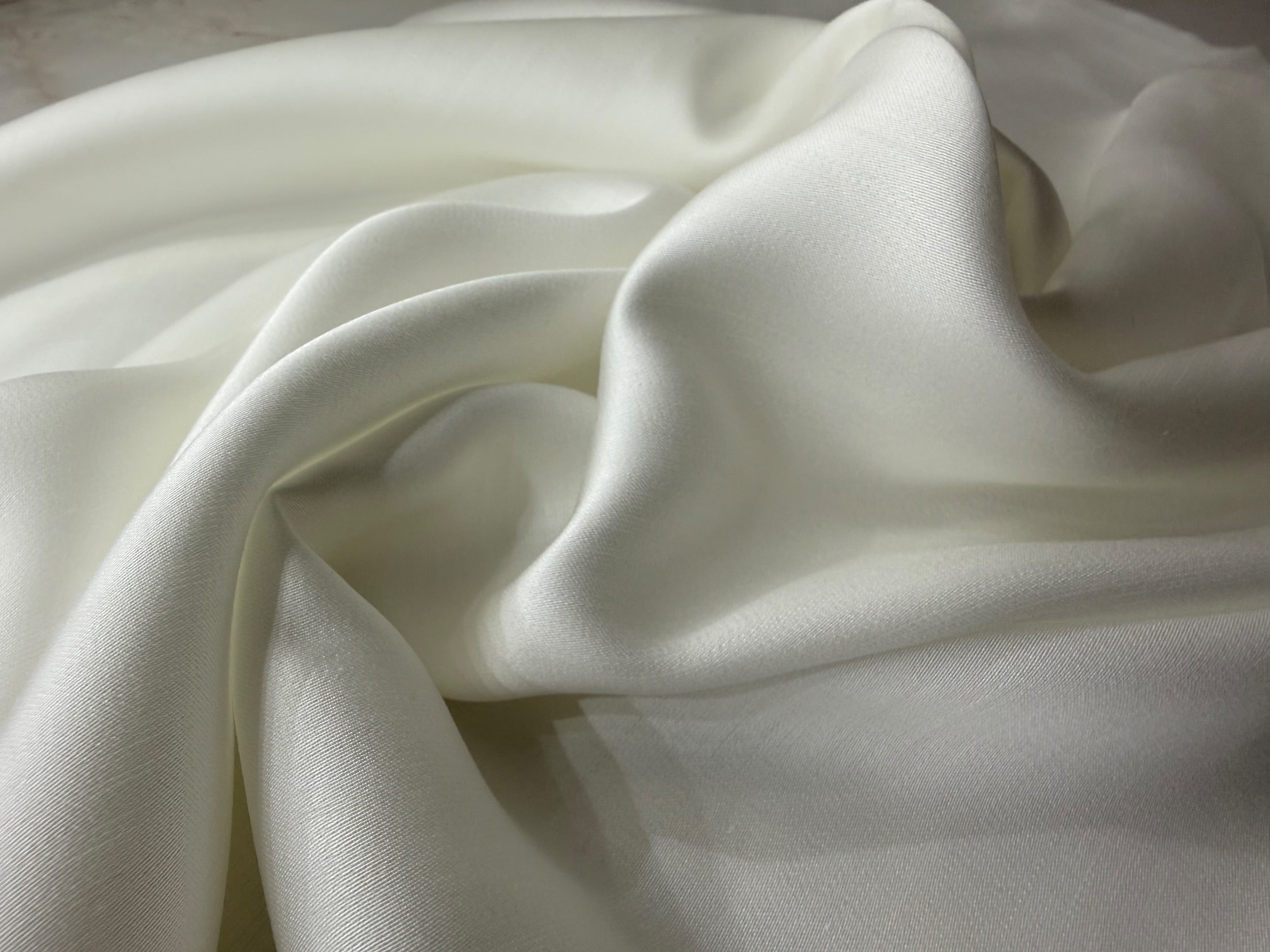 Nordhavn Living Aurora Satin Bettwäsche in Weiß (Quiet White): Nahaufnahme der seidigen Tencel-Satin Webstruktur mit sanftem Glanz und weichem Fall.