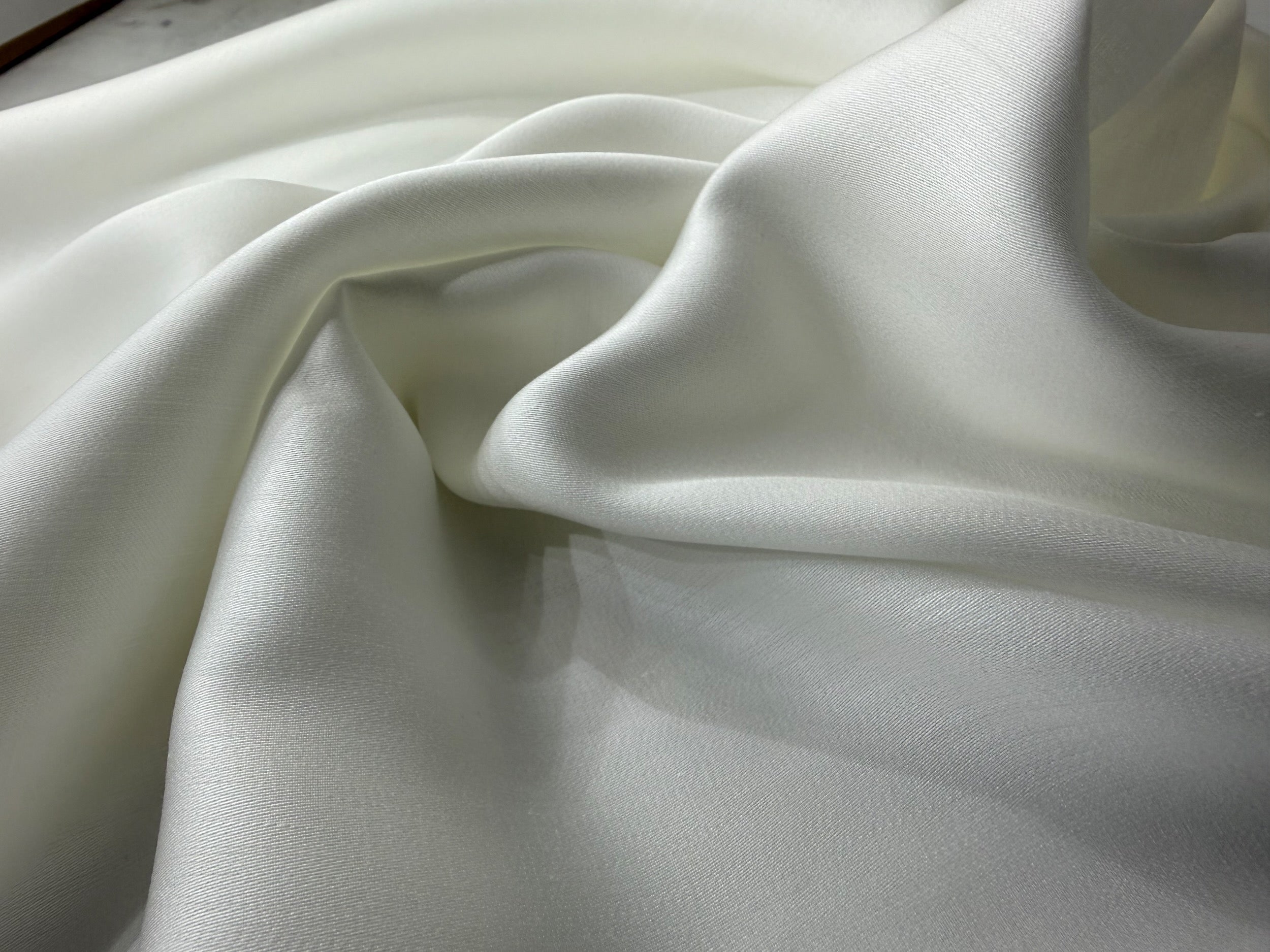 Nordhavn Living Aurora Satin Bettwäsche in Weiß (Quiet White): Detailaufnahme des seidigen Faltenwurfs und der glatten Tencel-Oberfläche.
