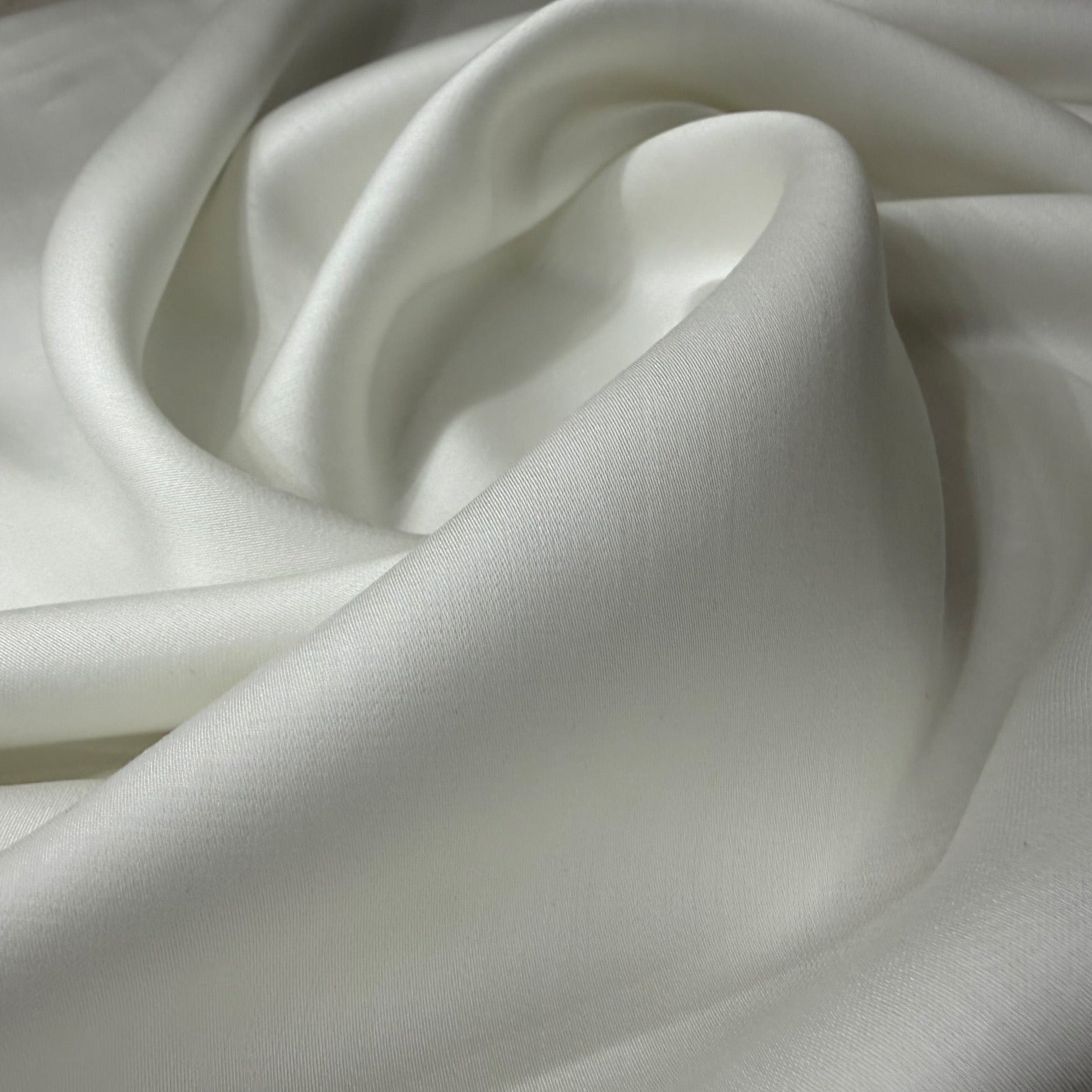 Nordhavn Living Aurora Satin Bettwäsche in Weiß (Quiet White): Detailaufnahme der weich geschwungenen Stoffbahnen, die den luxuriösen Satinglanz und die glatte Haptik betonen.