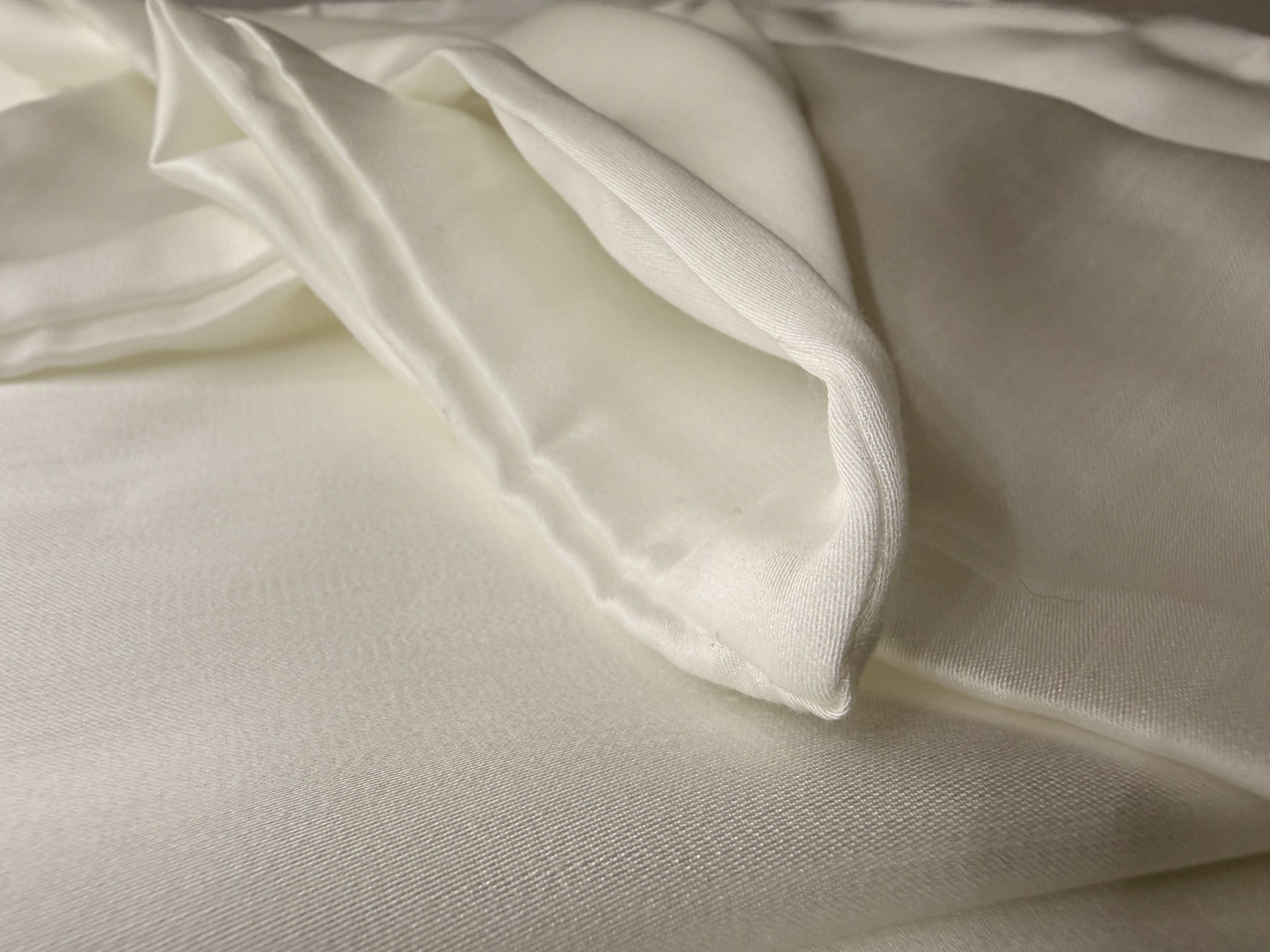 Nordhavn Living Aurora Satin Bettwäsche in Weiß (Quiet White): Detailansicht der sauber genähten Saumkante und der feinen Struktur des Tencel-Satins.